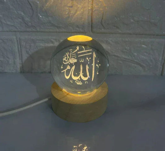 Illuminated crystal ball lamp with Arabic calligraphy on wooden base against textured wall