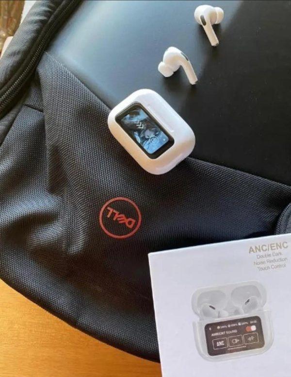 white wireless earbuds with digital display and charging case on black Dell laptop bag and wooden table