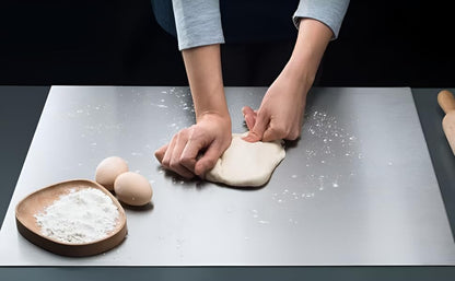 Person kneading dough on a floured surface with eggs and flour nearby.