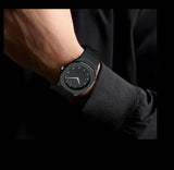 Minimalist black wristwatch with black dial and metal strap on a person's wrist