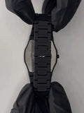 Black metal wristwatch band with clasp, held by gloved hands on a white background